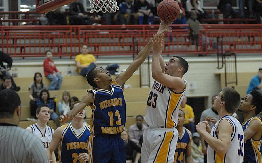 Mannheim junior Sam Rosario shoots over Wiesbaden senior Victor Strange during the Bison's 55-53 victory Friday night at Mannheim's Benjamin Franklin Village Sports Arena.  It was the final regular-season game for Mannheim High School, which is closing.