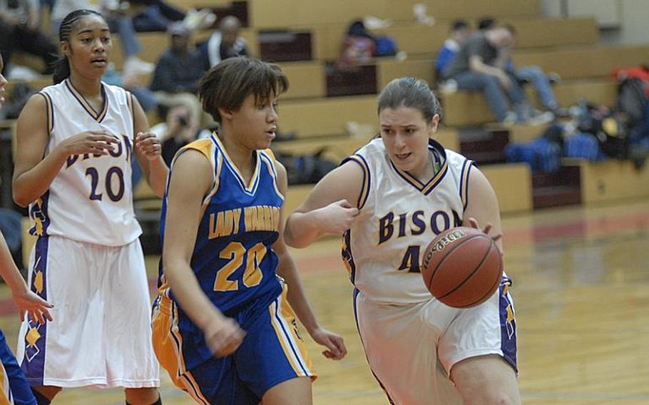 Mannheim sophomore Brittany Hyde tries to take the ball past Wiesbaden  defender LeAndra Thomas as Bison junior Kadedra Lea looks on during Friday night's game at Mannheim's Benjamin Franklin Village Sports Arena.  The game marked the Lady Bison's final regular-season home match in the school's history.