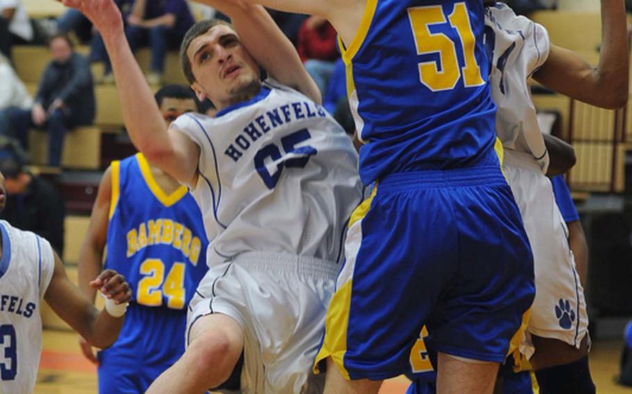 Chris Sanchez of Hohenfels, left, gets tangled up with Bamberg's  Dillon Leudtke as he goes to the basket in the DODDS Europe Division II boys basketball championship game. Hohenfels won, 51-37.