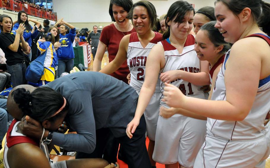 Menwith Hill assistant coach Michael McCreary hugs his daughter Monique as her teammates and coach Kathleen Ojeda gather round to celebrate the Lady Mustangs' Division III title win over Rota. Monique was injured late in the game and could not return to the game. The Lady Mustangs won, 38-35.