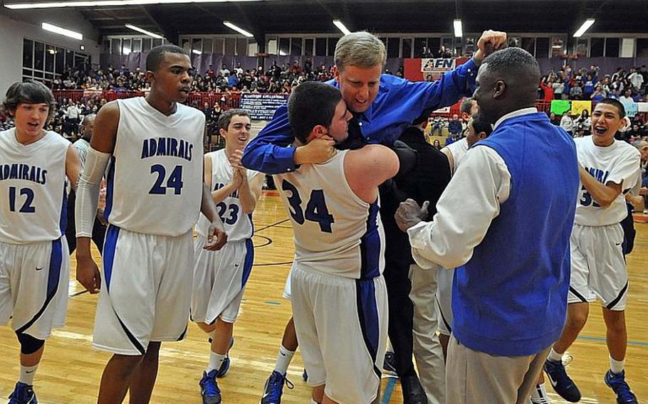 Rota's Tim Drake lifts coach Ben Anderson in a bear hug as the Rota Admirals celebrate their 65-61 win over Sigonella in the  DODDS Europe Division III boys basketball final. From left are Nick Holland, Tre'von Owens, Niko Fichera, Drake, Anderson, assistant coach Jeffery Shelton and Sean Mowrey.