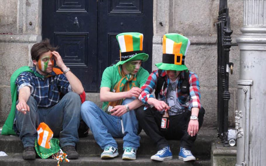 Three revelers at 2010 festivities take an afternoon break on Wellington Quay across from the Ha'penny Bridge in Dublin.