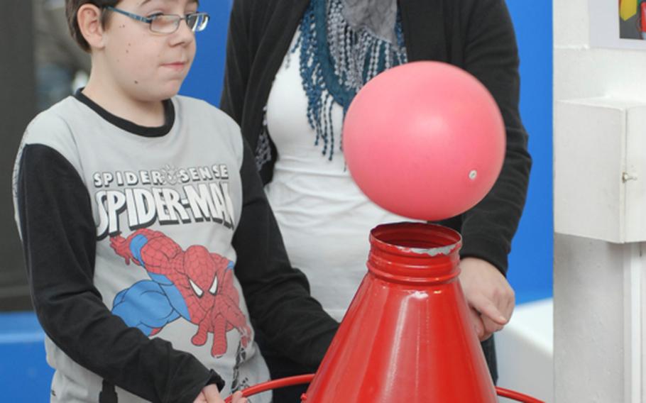 A visitor to the Kinder-Akademie Fulda in Fulda, Germany, tries to keep a ball floating with a bottle-shaped contraption pushing out air.