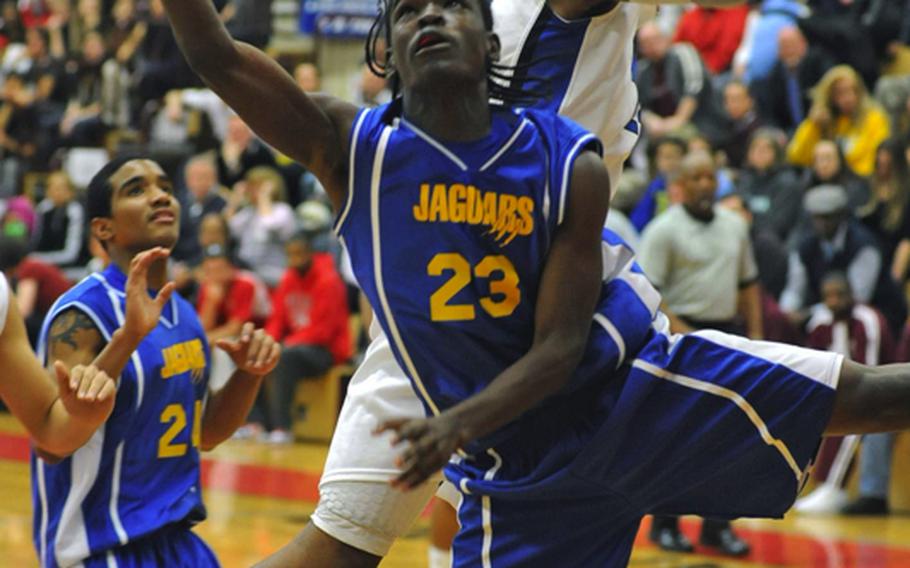 Sigonella's Larry Stevenson uses an acrobatic move to get past Rotas Tre'von Owens in the Division III title game. Both were named to the All-Europe first team in basketball.