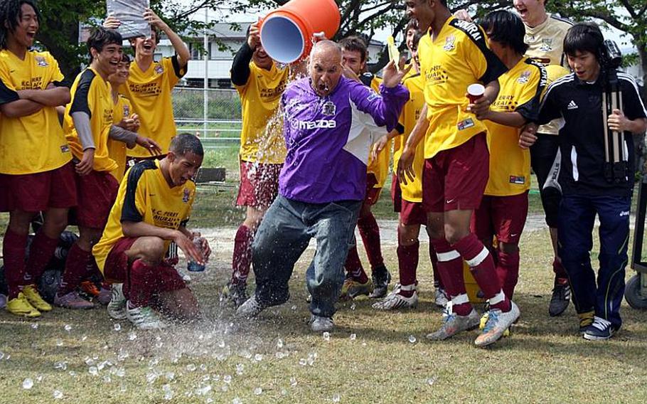 Matthew C. Perry  boys soccer coach Mark Lange gets the traditional water-bucket shower to the amusement of his players after Saturday's championship match in a six-team DODDS Japan regular-season tournament at Matthew C. Perry High School, Japan. Perry blanked Nile C. Kinnick, 1-0, and ran its school-best regular-season record to 14-1-1.