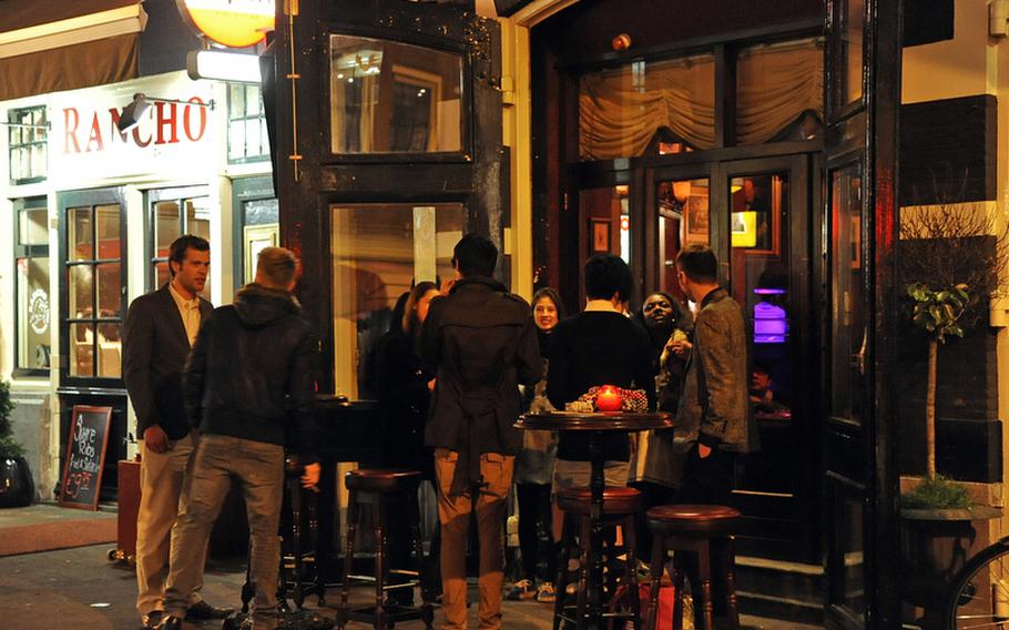 People enjoy a smoke, drink and conversation on the restaurant-lined Reguiliersdwarsstraat.