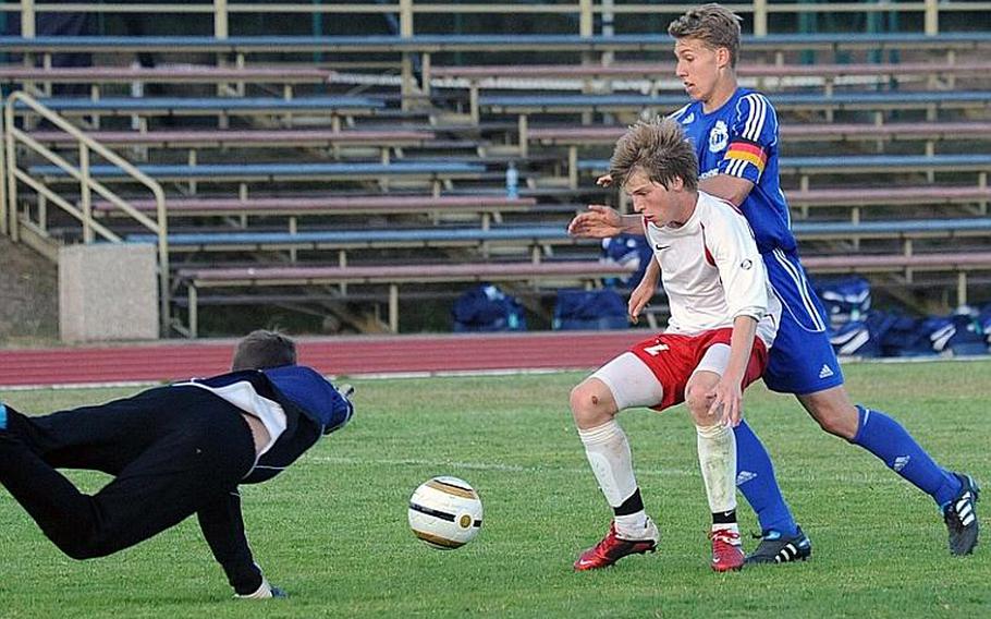 With the help of teammate Ryan McDonnel, Lakenheath keeper Joshua Dinsmore makes a leaping stop on Ramstein's Jonathan McLouth, right, The Royals won the game, 2-1, and McLouth was the tourney MVP for the division.