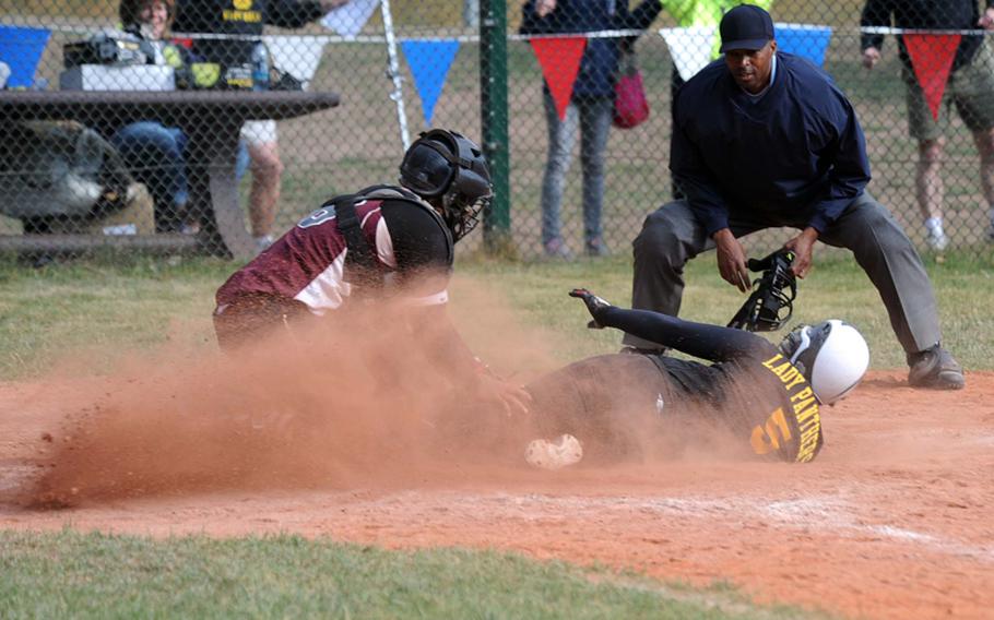 Patch's Bianca Lopez slides under the tag of Vilseck catcher Derej McClinton to score the winning run in a Division I semifinal game at the DODDS-Europe softball championships in Ramstein. Patch will meet Ramstein in Saturday's title game after the Royals beat Kaiserslautern 10-7. Plate umpire John Robinson gets ready to make the call.