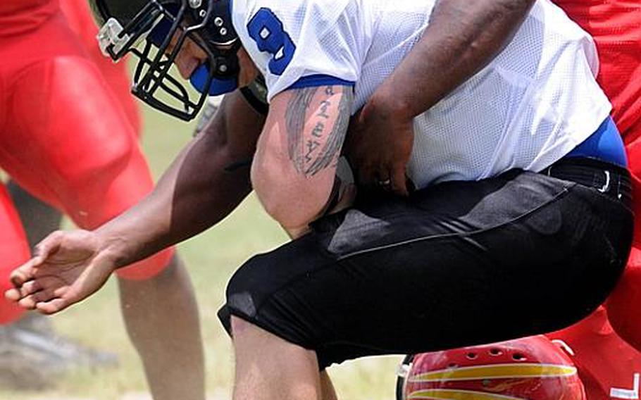 Kadena Dragons quarterback Jason Young gets wrestled to the ground by Foster Bulldogs defender Josh Reed during Saturday's U.S. Forces Japan-American Football League South Division game at Camp Foster, Okinawa. Foster won 30-14 and took a 11/2-game lead in the division over Kadena and Joint Task Force, each 0-1.