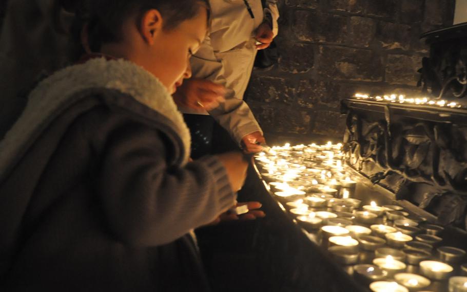 A boy places a candle in front of a Pieta figure in the church at the Maria Laach Abbey. Visitors can also write prayer requests on scraps of paper, which are collected in a box by the monks.