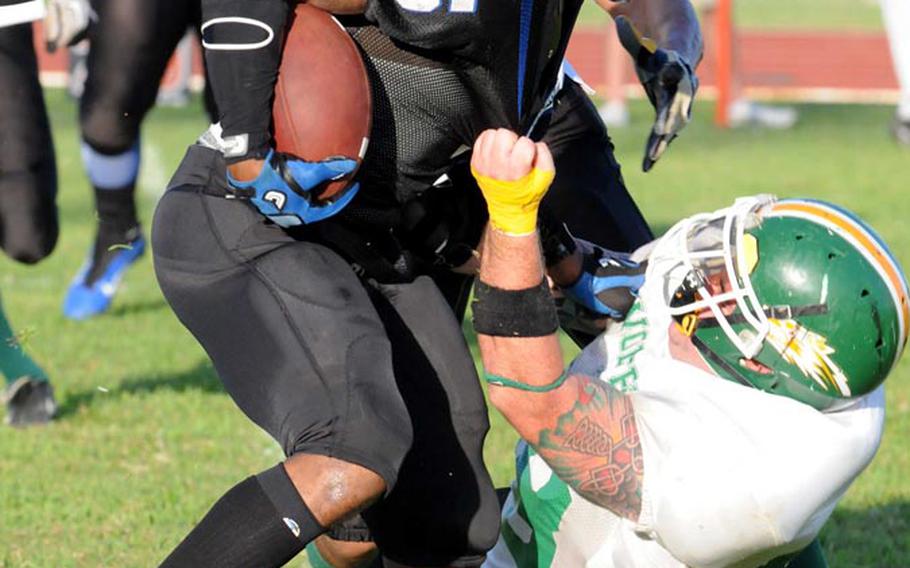 Joint Task Force Wolfpack lineman Christopher McCreight gets a fistful of jersey on Kadena Dragons running back Emanuel Griffin (5) during Saturday's U.S. Forces Japan-American Football League South Division first-round playoff game at Camp Foster, Okinawa.