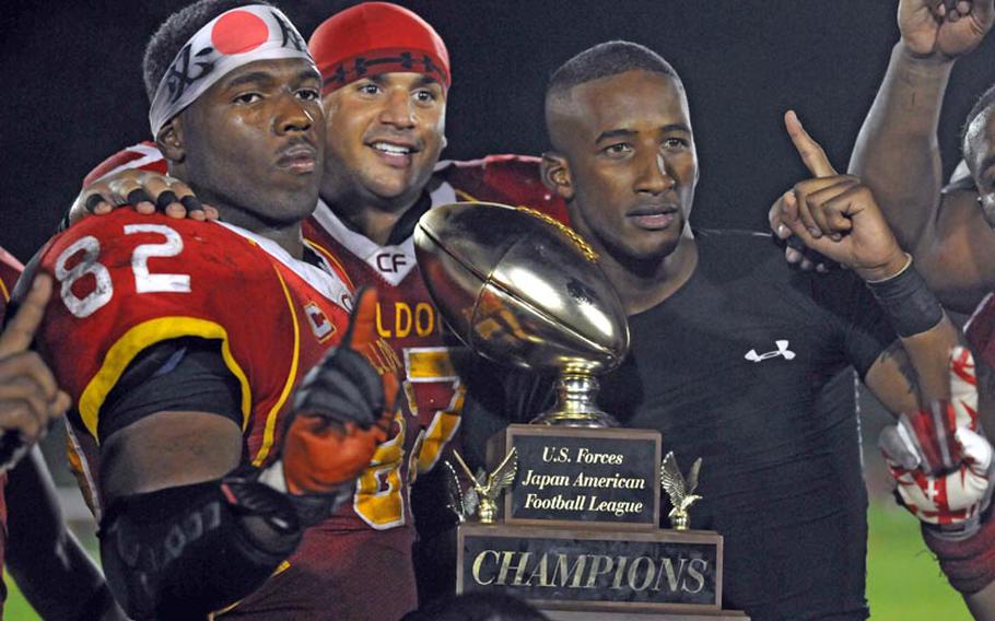 Foster Bulldogs Rohan Paul, Zach Zindler and Roger Veal celebrate with the U.S. Forces Japan-American Football League's traveling trophy after Saturday's Torii Bowl league title game at Misawa Air Base, Japan. The Bulldogs rallied from a 20-2 deficit to beat the Misawa Jets 24-20, the first road victory in Torii Bowl history and the second USFJ-AFL title for Foster in three seasons.
