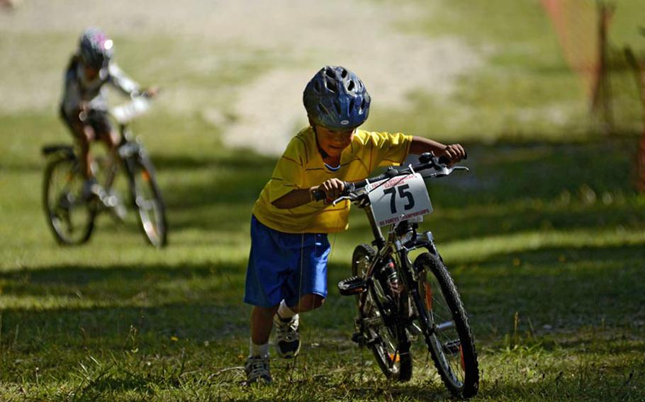 Jeison Huerta, 8, pushes his bike up a steep section of the Fat Tire Spectacular Mountain Bike Race in Garmisch, Germany, with his sister Ana Maria, 10, not far behind.