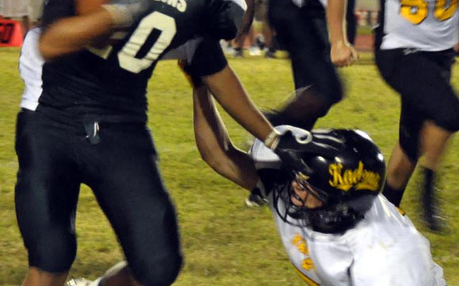 Kubasaki Dragons running back Roland Hernandez stiff-arms Kadena Panthers defender Justin Sego running around right end for a 19-yard gain during Friday's Okinawa Activities Council high school football game at Kubasaki High School, Okinawa. Kadena won 15-14.