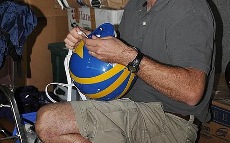 Dan Brickl, the Schweinfurt High School athletic director, prepares a helmet donated by neighboring Ansbach High School prior to a Sept. 8 practice.