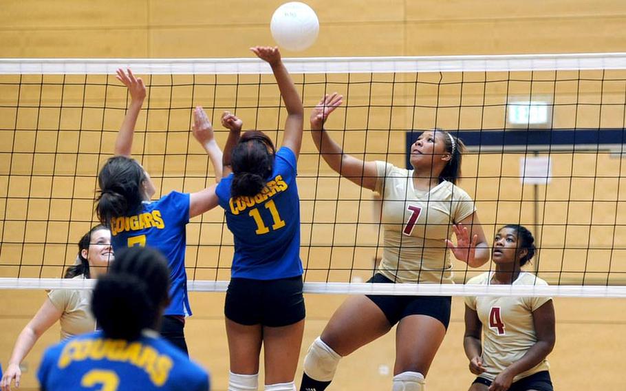 Ansbach's Dani Miller and Akira James, from left, try to block a return by Vilseck's Deraj McClinton in a match in Wiesbaden on Saturday. Vilseck won 25-18, 25-13, 25-18. At right is Mariah Morris.