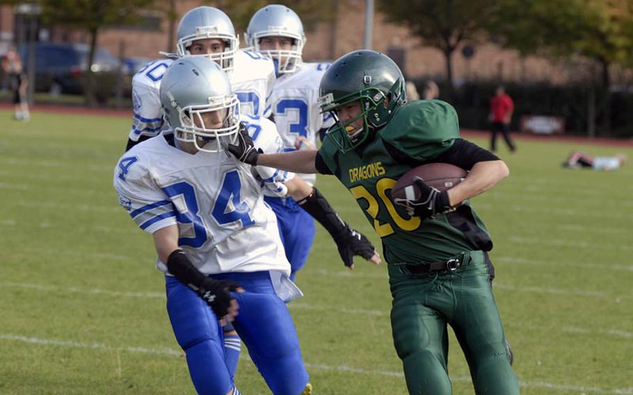 Alconbury running back Keith Marasigan, a junior, stiff arms Brussels defender Will Cole, sophomore, on his way to a 58-yard touchdown run, Saturday 24, at RAF Alconbury in England. The Dragons won the game 44-6.