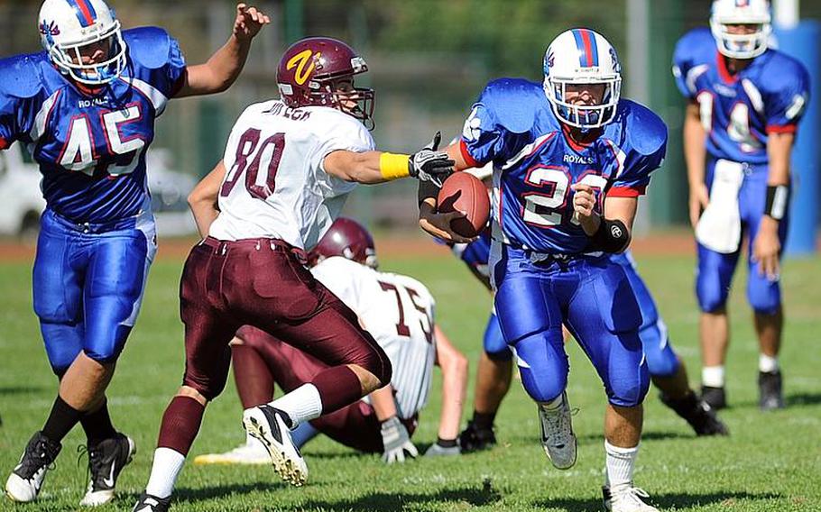 Ramstein's Jon Grotelueschen, right, gets past Vilseck's Luis Guzman for a big gain in the Royals' 28-0 homecoming win over the Falcons on Saturday. Grotelueschen scored three touchdowns on the day. At left is Drake Harness.