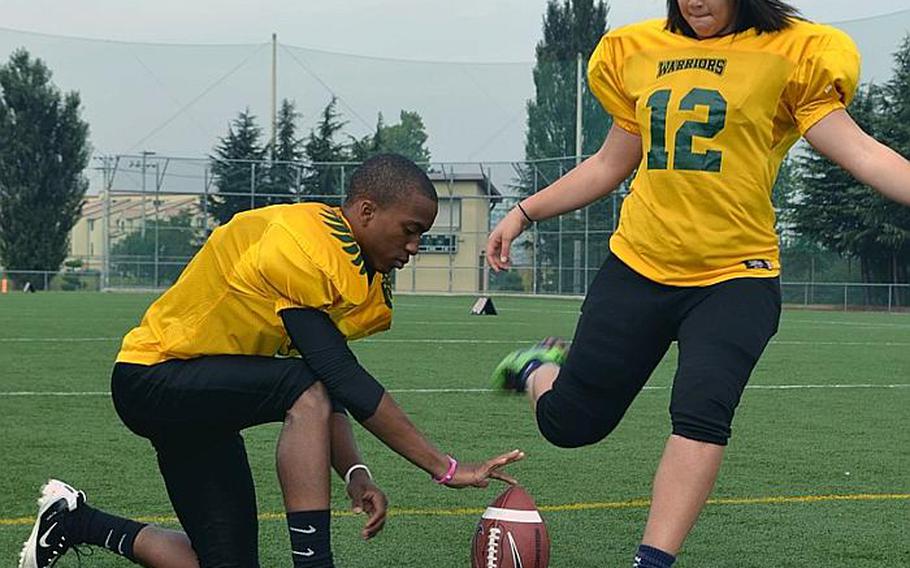 Daegu American Warriors quarterback Darius Wyche places the ball for sophomore kicker Haley Claiborne during practice Monday at Camp Walker, South Korea. Claiborne, an All-Far East soccer stopper, is the second girls player to suit up for Daegu football in six years, following Joanne Youngblood in 2005.