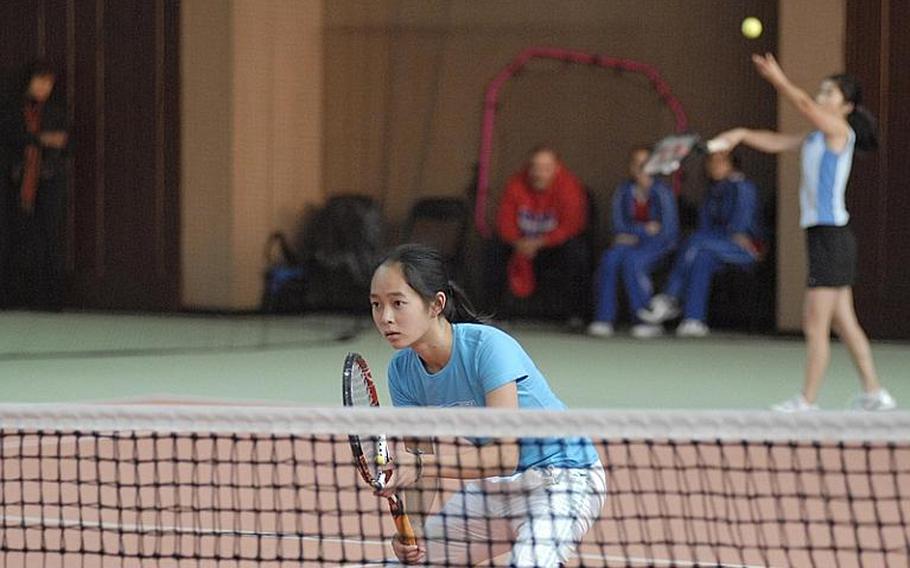 International School of Brussels junior Sayaka Goto looks across the net as freshman teammate Haley Tan gets ready to serve the ball during girls doubles action on Friday at the Hochheim Tennis Center.