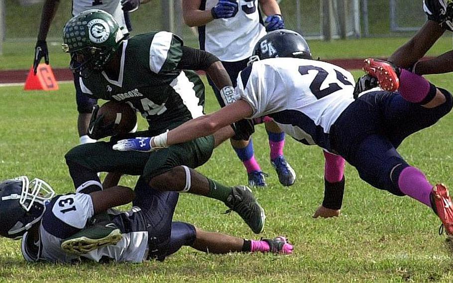 Kubasaki's Brandon Crawford is tackled by Seoul American's Edward Moore  and Devin Williams during Saturday's Far East High School Division I football semifinal at Kubasaki High School, Okinawa. The Dragons beat the visiting Falcons 22-7.