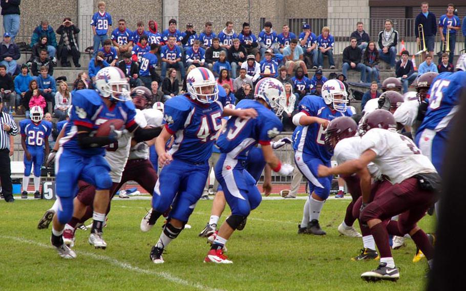 Ramstein fullback Drake Harness  prepares to take on Vilseck linebacker Riley Fees  and lead Jon Grotelueschen, left, to positive yardage during the Royals' 24-21 victory Saturday over the Vilseck Falcons in a European Division I semifinal game at Ramstein. Grotelueschen, a 6-foot-2, 210-pound senior, rushed 29 times for 152 yards.