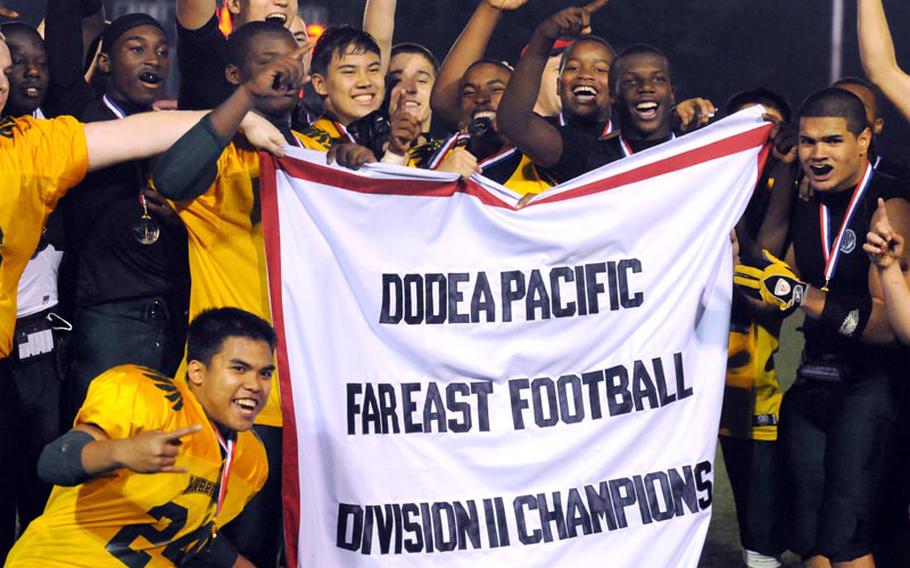 Daegu High School Warriors players celebrate their second straight Far East High School Division II football championship banner after Saturday's championship game at Camp Walker, South Korea. The Warriors beat the Zama American Trojans 7-3.