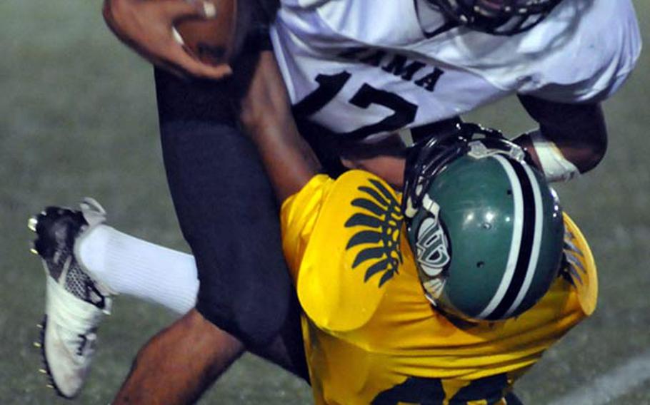 Zama American Trojans running back Mitchell Harrison is dragged down by Daegu Warriors defender Keyonte Bennett Saturday's championship game at Camp Walker, South Korea. The Warriors beat the Trojans 7-3.