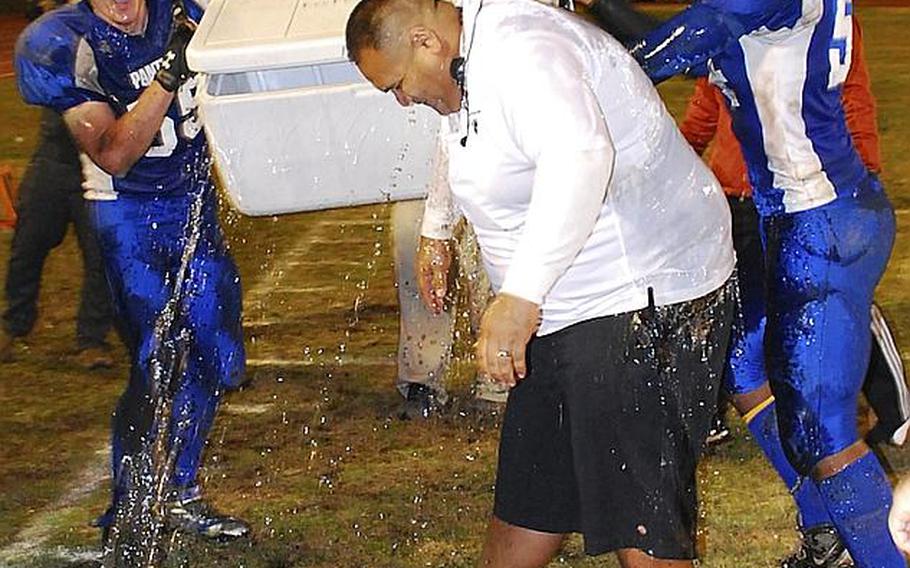 Yokota Panthers Jesse Christmas and Jerrell Fuller give defensive coordinator Ernie Carrasco the water-bucket treatment after their 34-6 victory Saturday over Kubasaki in the Far East Division I championship game. It was Yokota's first D-I title in school history.