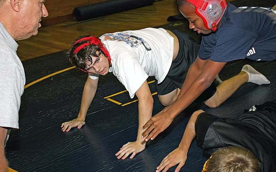 Matthew C. Perry junior wrestlers Stephen Brown and Charles Jackson work with volunteer assistant coach Mark Livingood, left, during the first day of Samurai wrestling practice at Marine Corps Air Station Iwakuni, Japan.