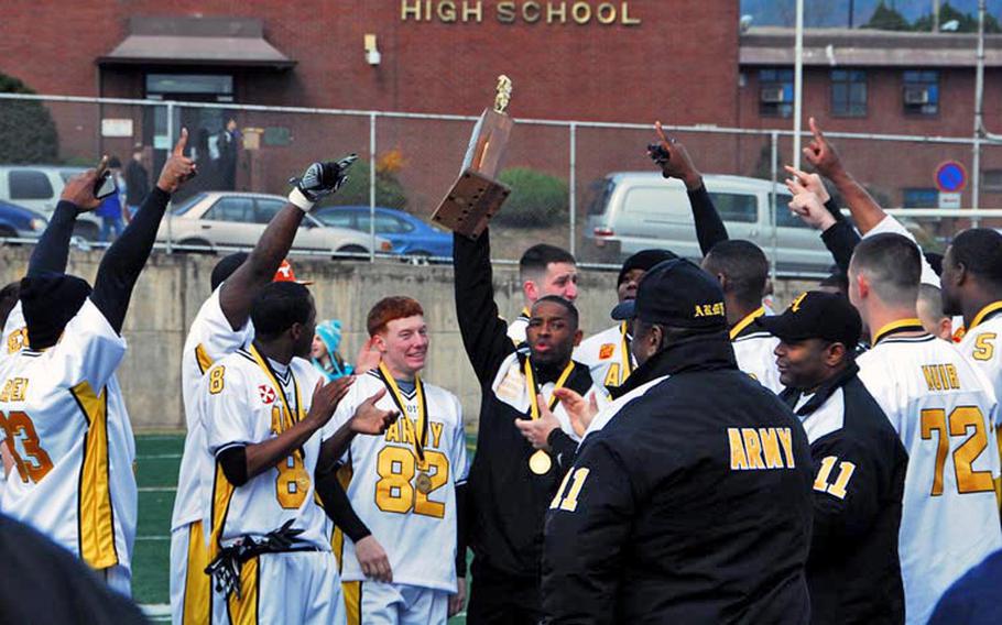 Army head coach Dennis Brown Jr. celebrates his fourth straight win against Navy with his players Saturday after the Army-Navy game at Seoul American High School.  Army, led by three touchdown passes by quarterback Jeremy Finney, won the game 30-0.