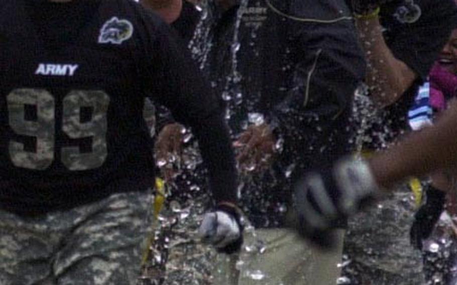 Army coach Lawrence Occomy gets the water-bucket bath treatment followin g Saturday's 22nd Okinawa Army-Navy flag football game at Torii Field, Okinawa. Army rallied from a 21-12 deficit to beat Navy 25-21.