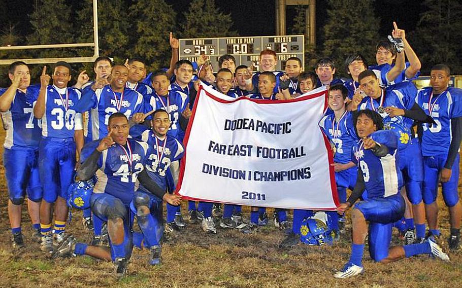 Yokota players celebrate with the banner after their 34-6 victory Saturday over Kubasaki in the Far East Division I championship game. It was Yokota's first D-I title in school history.