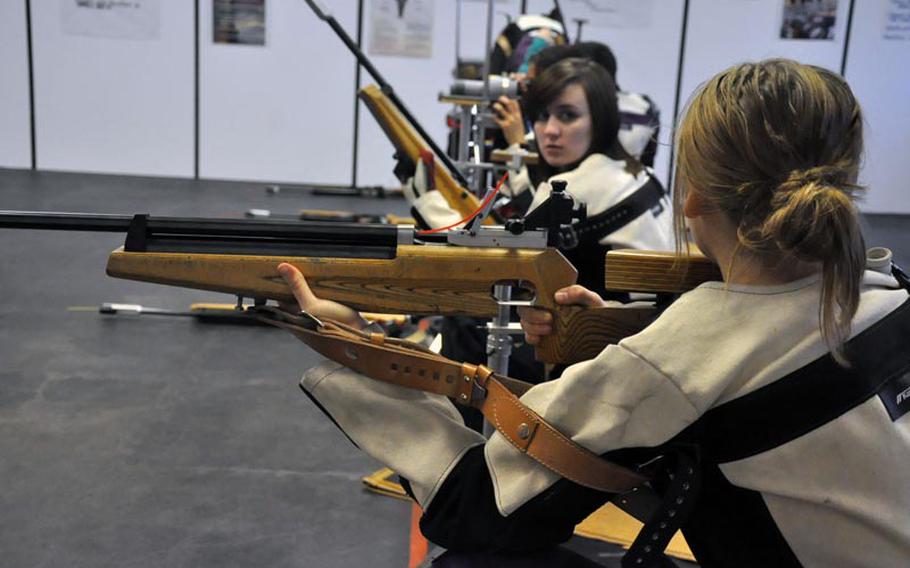 Freshman Elizabeth Booher of Ansbach chats with Alicia Anderson, foreground, prior to shooting from the kneeling position Saturday in Ansbach. The Cougars finished second overall in team scoring with 1,344 points.