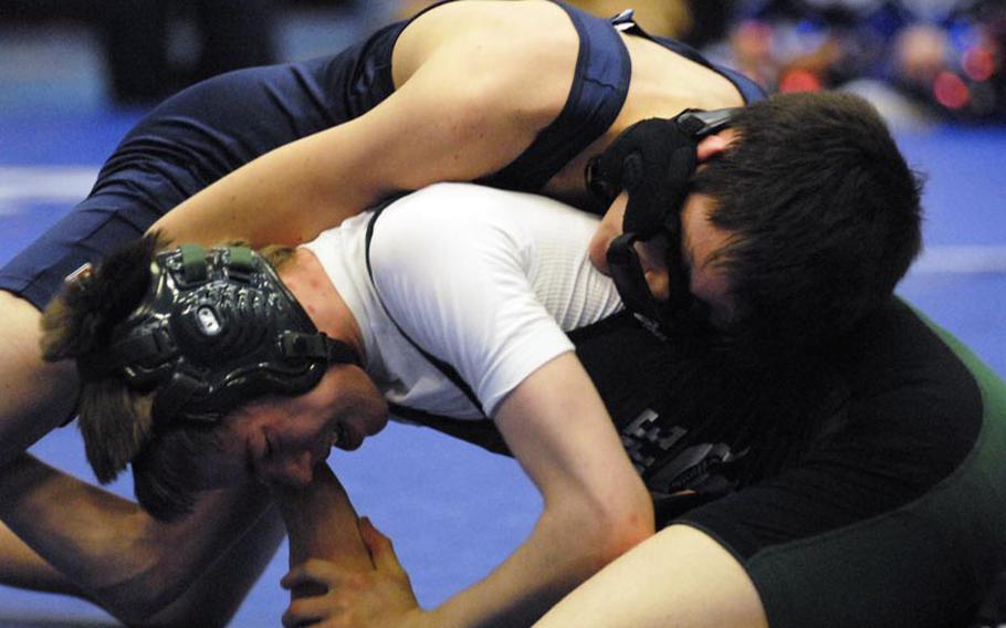 Black Forest Academy sophomore Thomas Althaus battles his slipping headgear to get in position against SHAPE junior Josh Crabtree during a first- round matchup in the 120-pound weight category at Ramstein High School.  Ramstein played host to a seven-team DODDS-Europe wrestling meet on Saturday.