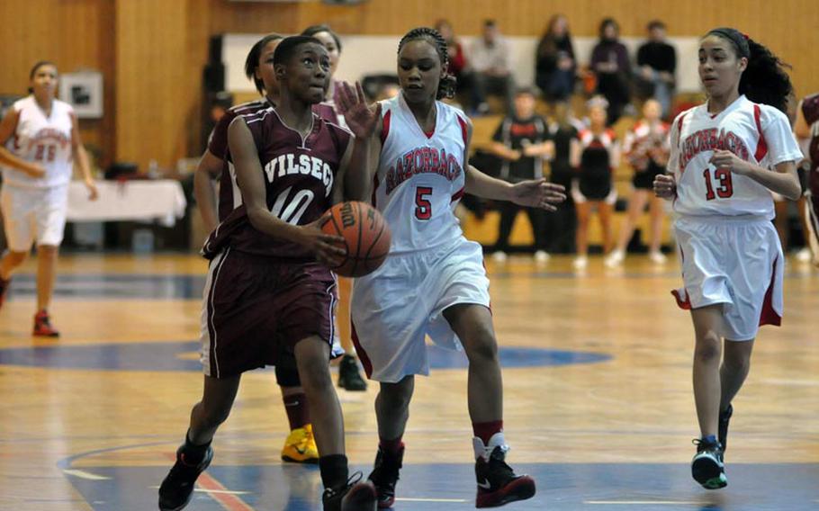 China Sumpter of Vilseck drives to the basket Saturday in Schweinfurt, Germany, the Razorbacks Santrice Jackson, left, and Mariel Jones give chase. The Lady Falcons won the game in overtime 36-32. Sumpter was the leading scorer with 19 points.