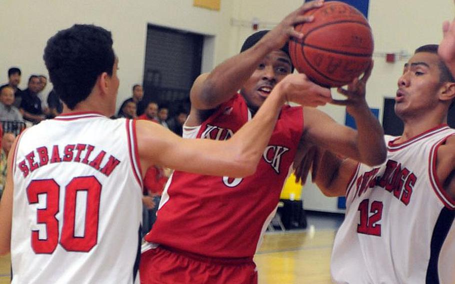 Nile C. Kinnick's Malik White drives between Okkodo's Josh Sebastian and Maksever Kepwe during Friday's semifinal game in the 63rd Far East High School Boys Division I Basketball Tournament at Naval Station, Guam. The Bulldogs downed the Red Devils 48-39.
