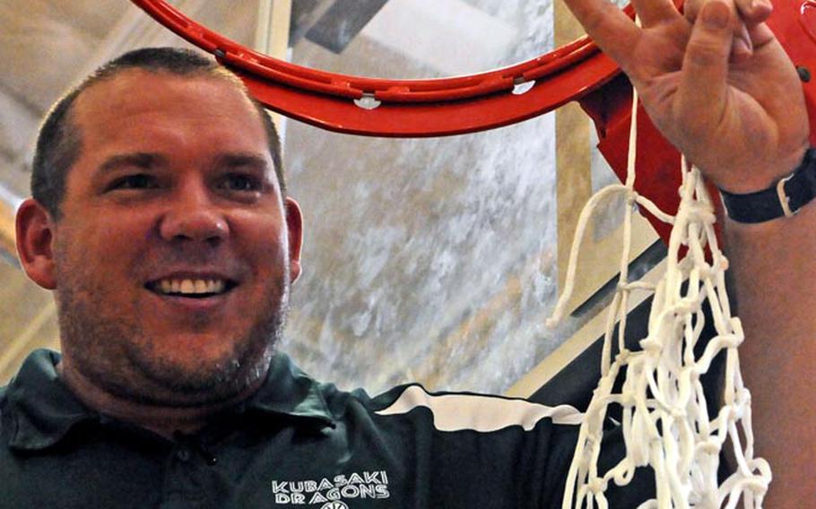 Kubasaki Dragons coach Jon Fick displays the souvenir net cords and indicates two for back-to-back titles after during the championship game of the 63rd Far East High School Boys Division I Basketball Tournament at Naval Station, Guam. Kubasaki defeated Okkodo of Guam 55-47 for its second straight title, its third in six years under Fick and its Pacific-record 11th.
