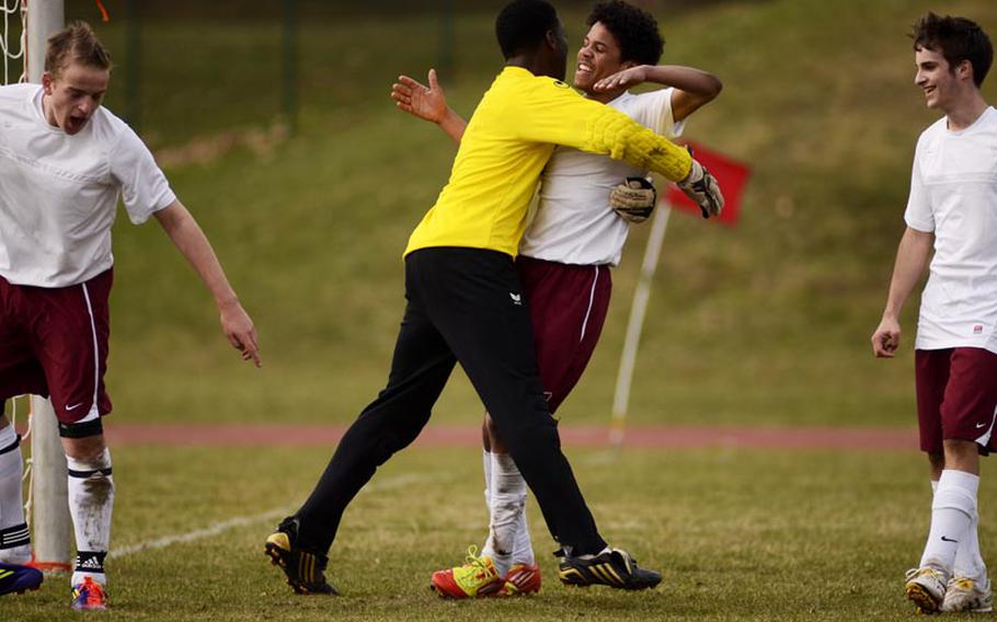 Baumholder's goalie, Desante Brown gives Devon Farmer a hug after Farmer slid to knock the ball out of the goal with teammates Christopher Beck, left, and Dominic Sparks looking on in Saturday's game in Baumholder, Germany. SHAPE won the game 8-0.