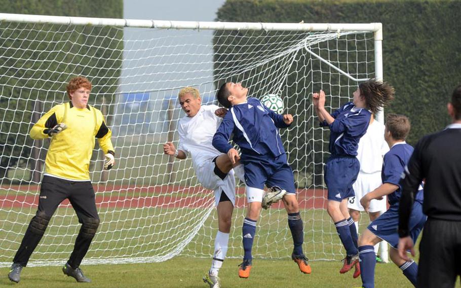 Bitburg's Dane Robbins attempts to head the ball into the net with Alconbury defender Tyler Grissett and goal keeper Chris Lanphear in on the action during Saturday's match at RAF Alconbury, England. Also on offense for Barons is Kyle Shaver. The Dragons won the match 6-1.