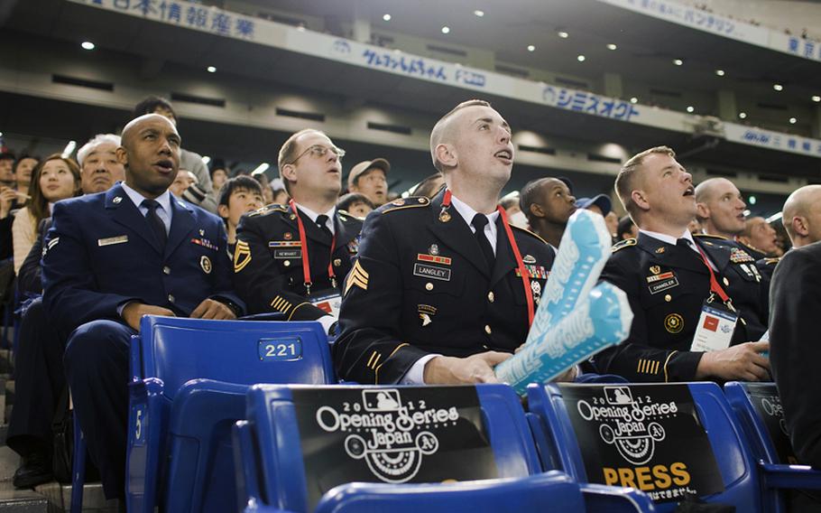 Servicemembers who took part in the opening ceremony watch the American League season opening MLB baseball game between the Seattle Mariners and the Oakland Athletics in Tokyo.