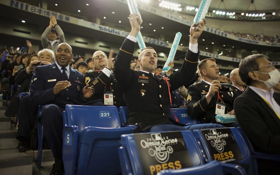 Servicemembers who took part in the opening ceremony watch the American League season opening MLB baseball game between the Seattle Mariners and the Oakland Athletics in Tokyo.
