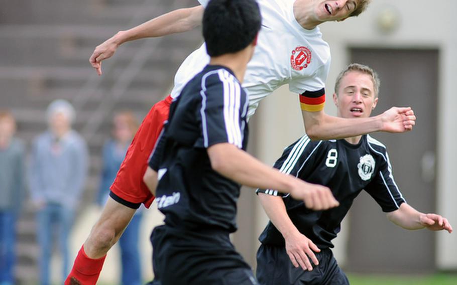 Kaiserslautern's Cody Tremaine gets his head under the ball in between Ramstein's James Cho, left, and Tim Taylor. The regular season finale ended 1-1, leaving the teams tied at 4-0-1 in Region II.