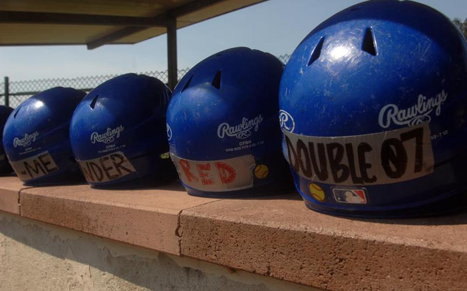 Batting helmets line a dugout wall during Thursday's opening games at the European high school softball championships at Ramstein High School.