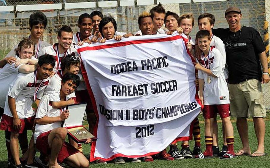 Matthew C. Perry Samurai boys soccer team members and coach Mark Lange celebrate with the title banner following the Samurai's 2-1 victory Friday over defending champion Yongsan International-Seoul in the Far East High School Division II Tournament at Camp Humphreys, South Korea. It was the Samurai's second title in three years.