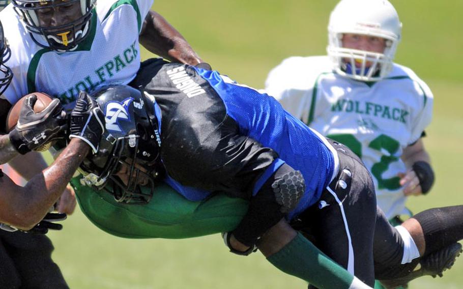 Camp Hansen Wolfpack running back Hasani Ferraro is lifted airborne by Kadena Dragons defender Julian Taylor during Saturday's U.S. Forces Japan-American Football League South Division regular-season finale at Camp Hansen, Okinawa. The Wolfpack rallied from an 8-2 deficit to beat the Dragons 24-8.