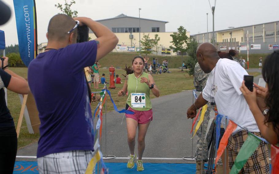 Sgt. Catalina Sandoval, 25, of the 57th Signal Company, crosses the tape as the first female finisher in Saturday's U.S. Forces-Europe Army Ten-Miler in Grafenwöhr, Germany. Sandoval, who finished with a time of 69 minutes, 5 seconds, was the first woman across the line and qualified to represent U.S. Army Europe at the Army Ten-Miler in Washington, D.C. in October.