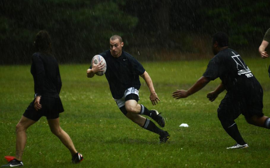 Chris O'Connor, a firefighter with the U.S. Air Force, runs the ball past defenders as it pours down rain during a recent practice session at Ramstein Air Base.