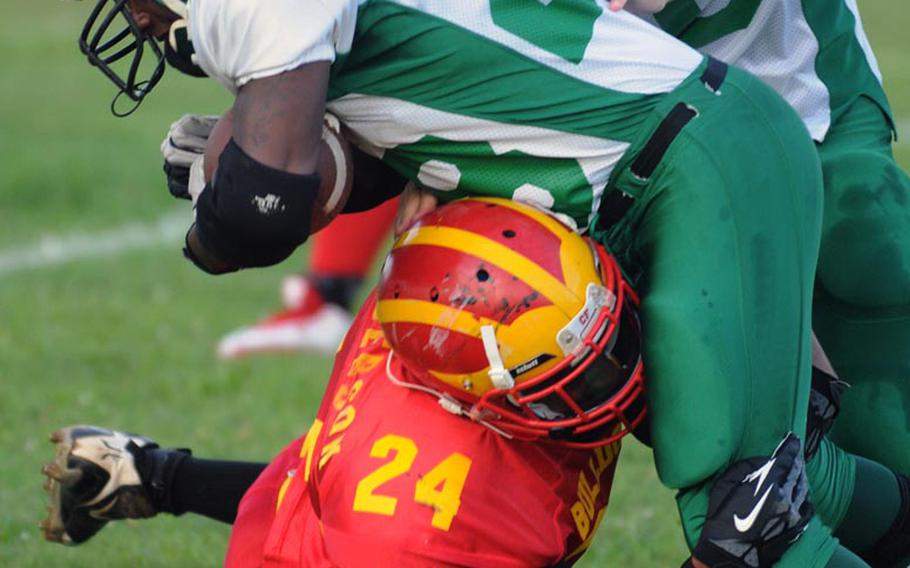 Camp Hansen Wolfpack running back Derek May gets wrapped up by Camp Foster Bulldogs defender Michael Henderson during Saturday's U.S. Forces Japan-American Football League South Division championship game at Camp Foster, Okinawa. The defending champion Bulldogs blanked the Wolfpack 32-0 to advance to their third Torii Bowl league title game in four years.