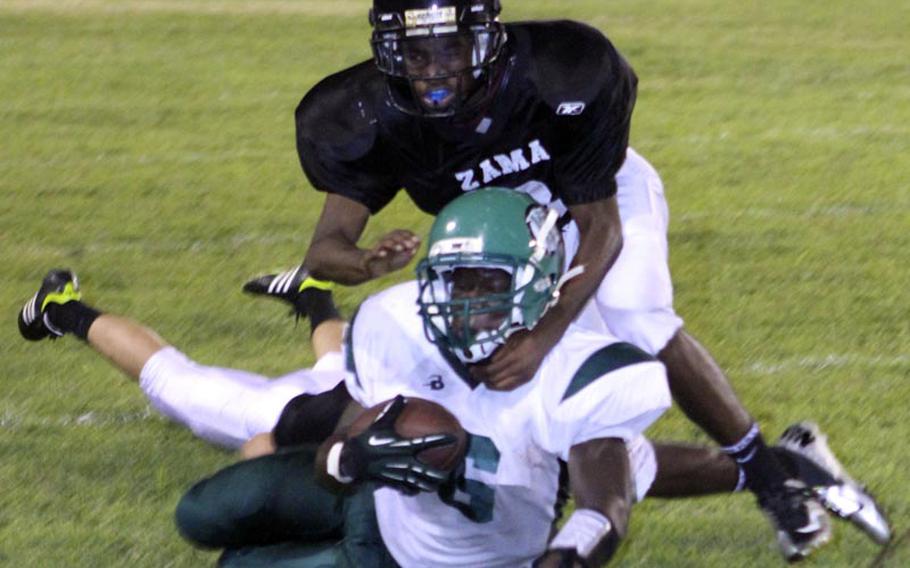 Daegu running back Ronald McLean is brought down by Zama defender RayVaughn King during Saturday's DODDS Pacific Division II football game at Camp Zama, Japan. The Trojans routed the two-time defending D-II champion Warriors 45-12.